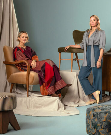 A portrait of two women posed against a collection of furniture