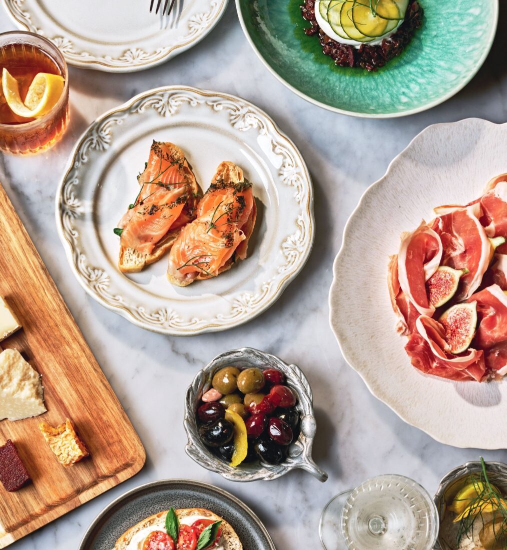 Salmon crostini, buffalo milk burrata, and prosciutto with figs on a table