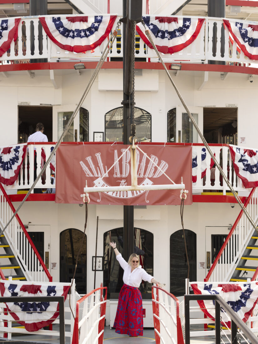 A woman stands on a boat decorated with fourth of july banners