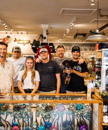 A group of people standing behind the counter in a fly fishing store.