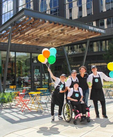a group of people outside a coffee shop with balloons