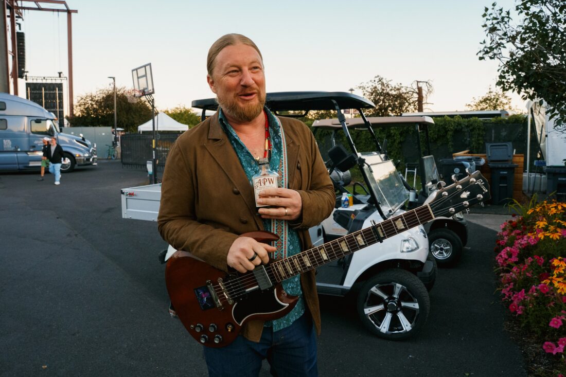 Derek Trucks holds a bottle of Ass Pocket Whiskey.