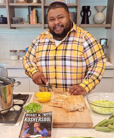 A portrait of a chef in a kitchen at a cutting board