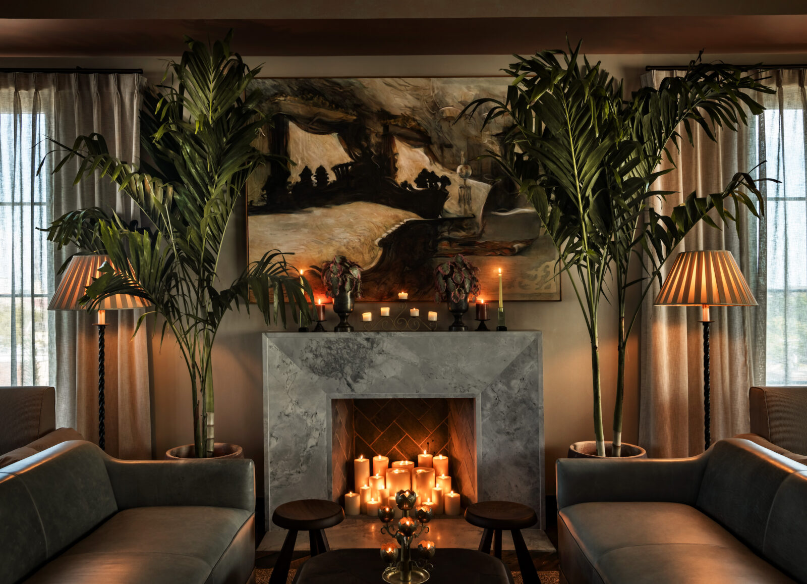 A lounge with a fireplace, palms, and an expressive abstract painting