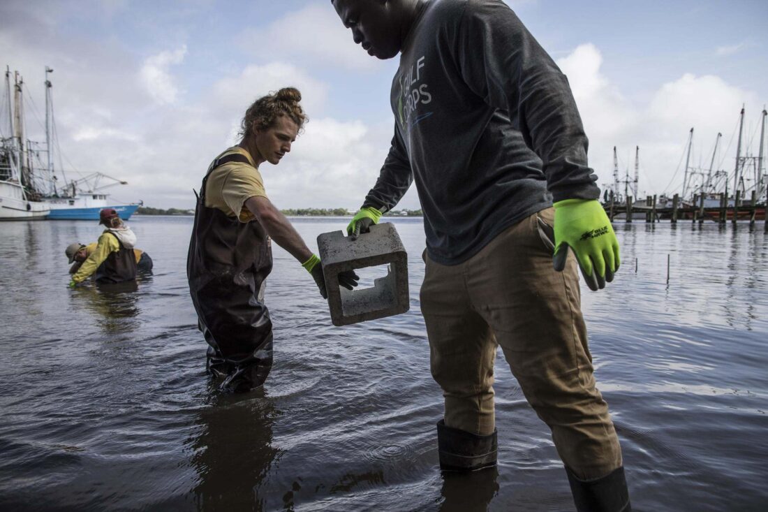 People pass cinder blocks in water